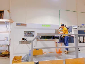 Factory worker operating a high-tech cutting machine in an industrial manufacturing facility.