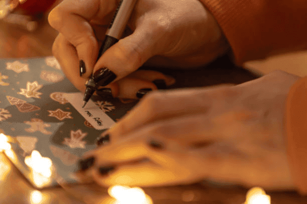 Hands writing on a festive card.