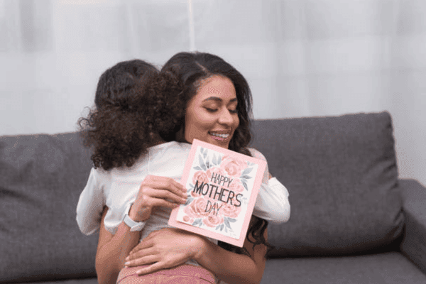 Mother and child sharing a heartfelt embrace with a Mother's Day card.