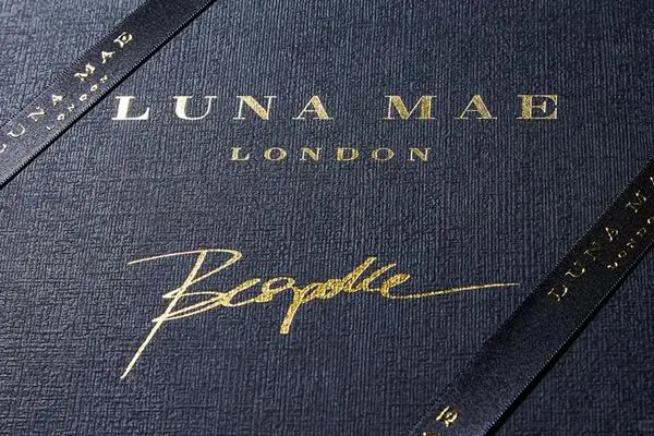 Close-up of apparel box materials with foil logo, textured paper, and tissue paper